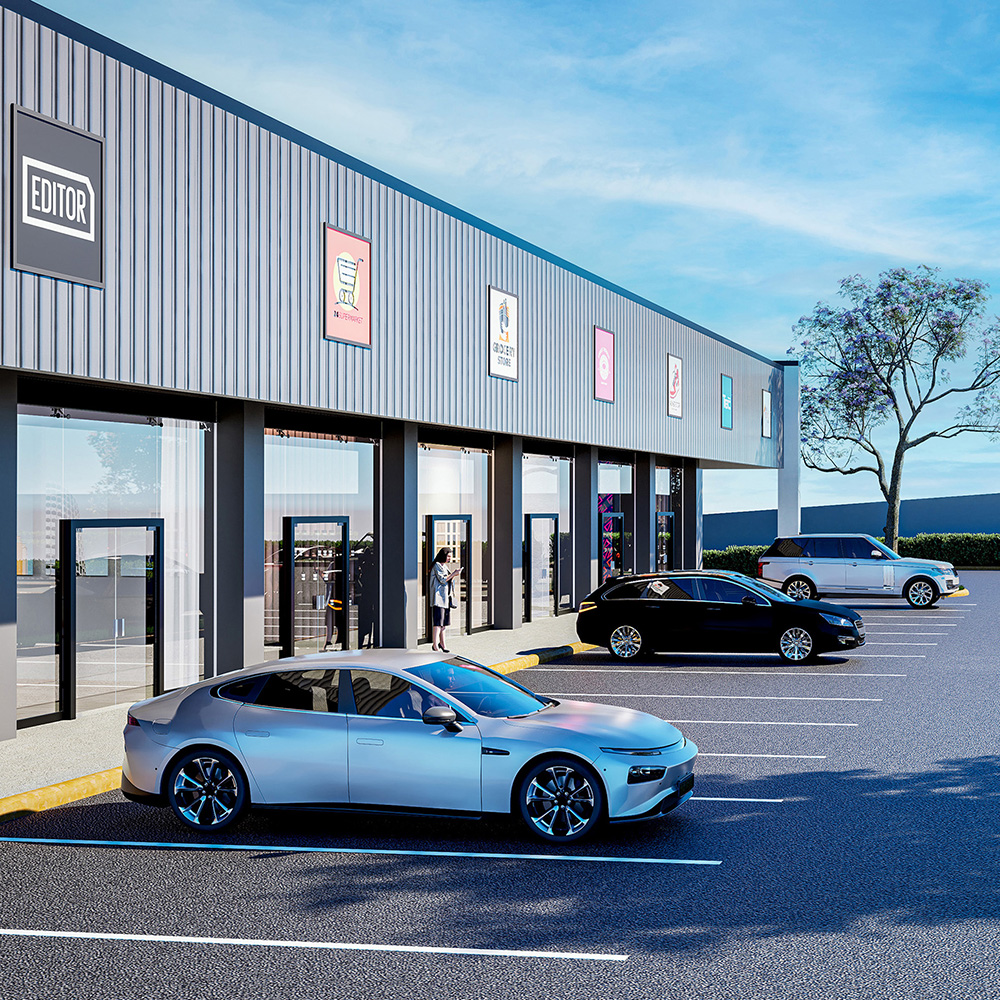 Vista desde la calle de locales comerciales con modernas fachadas de vidrio y amplio parqueo al frente